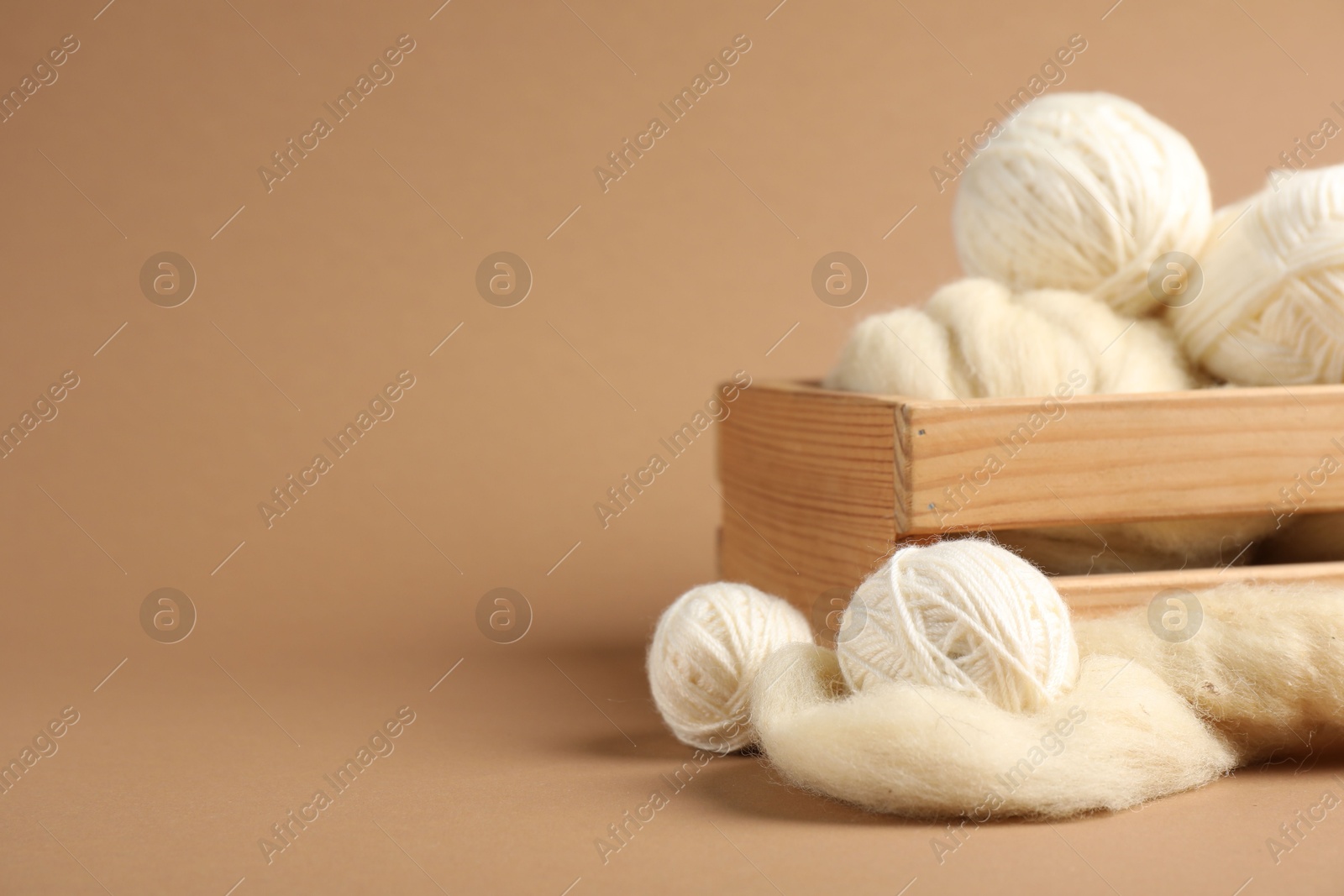 Photo of Felting wool and knitting yarn on brown background, closeup. Space for text