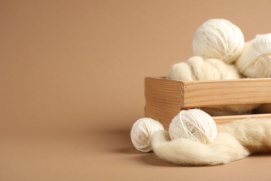 Photo of Felting wool and knitting yarn on brown background, closeup. Space for text