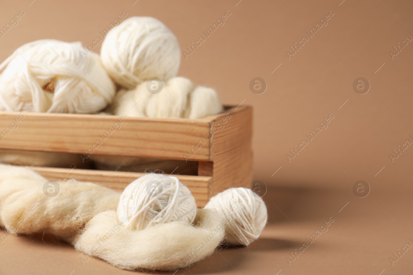 Photo of Felting wool and knitting yarn on brown background, closeup. Space for text