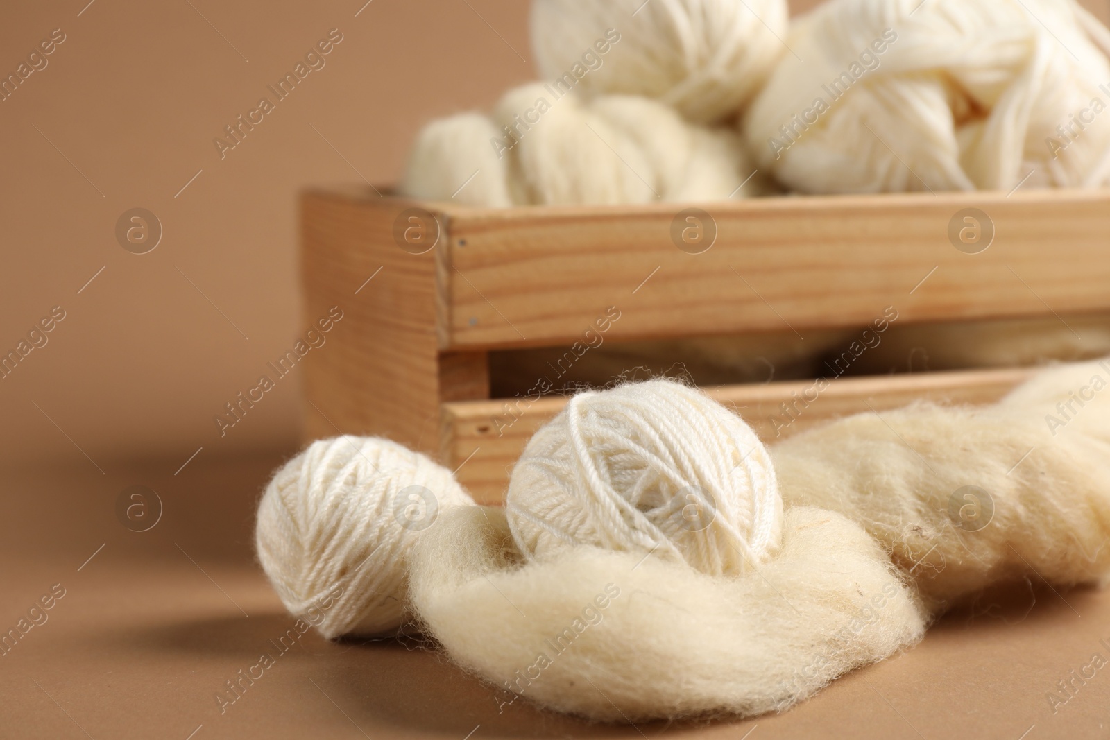 Photo of Felting wool and knitting yarn on brown background, closeup