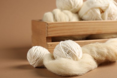 Photo of Felting wool and knitting yarn on brown background, closeup