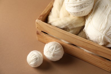 Photo of Felting wool and knitting yarn on brown background, closeup