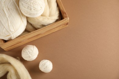 Photo of Felting wool and knitting yarn on brown background, above view. Space for text