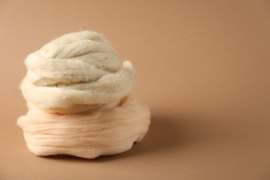 Photo of Natural felting wool on brown background, closeup. Space for text