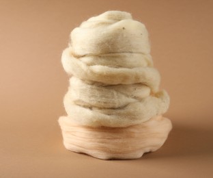 Photo of Natural felting wool on brown background, closeup