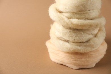 Photo of Natural felting wool on brown background, closeup. Space for text