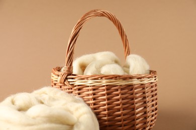 Photo of Felting wool in basket on brown background, closeup