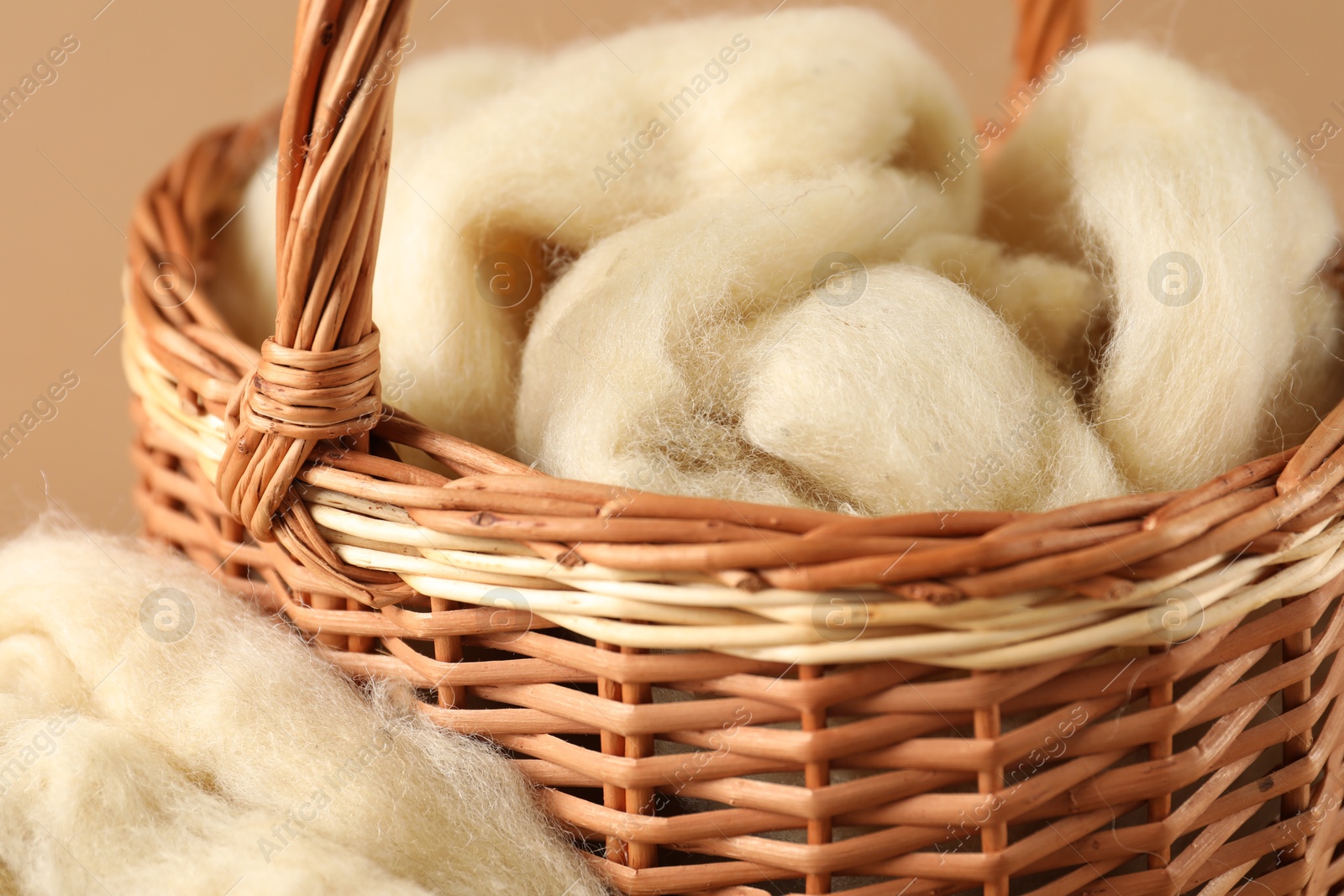 Felting wool in basket on brown background, closeup Photo of Felting wool in basket on brown background, closeup