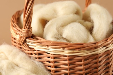 Photo of Felting wool in basket on brown background, closeup