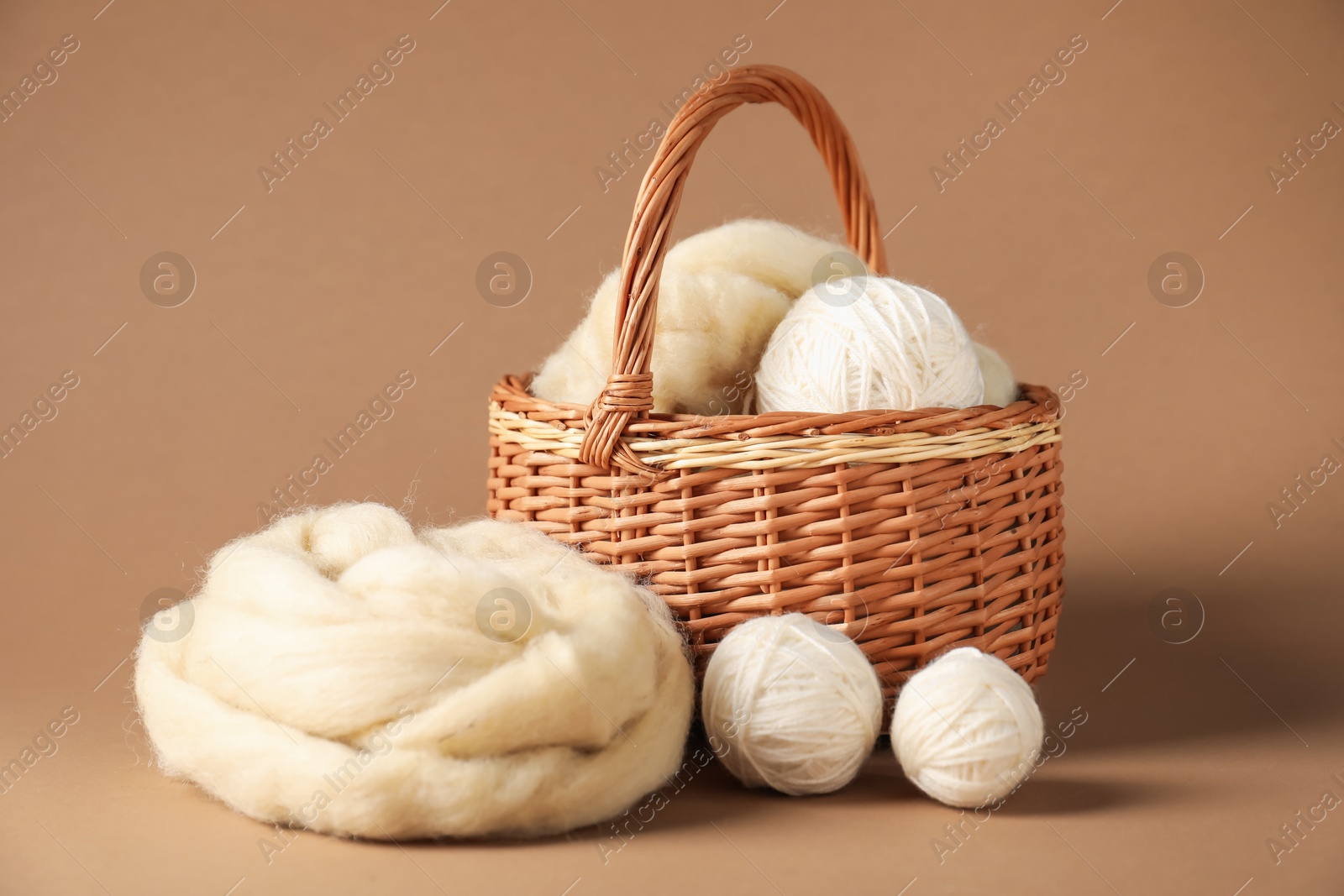 Felting wool and knitting yarn on brown background Photo of Felting wool and knitting yarn on brown background