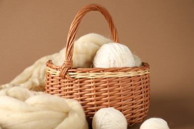 Photo of Felting wool and knitting yarn on brown background, closeup