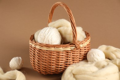 Photo of Felting wool and knitting yarn on brown background, closeup