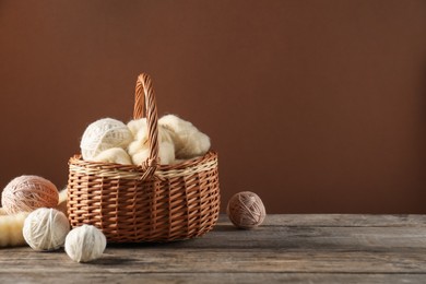 Photo of Felting wool and knitting yarn in basket on wooden table. Space for text
