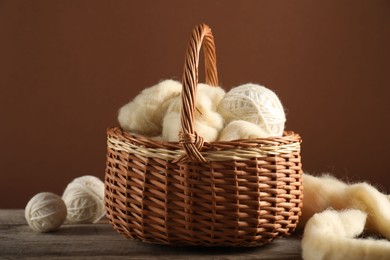 Photo of Felting wool and knitting yarn in basket on wooden table