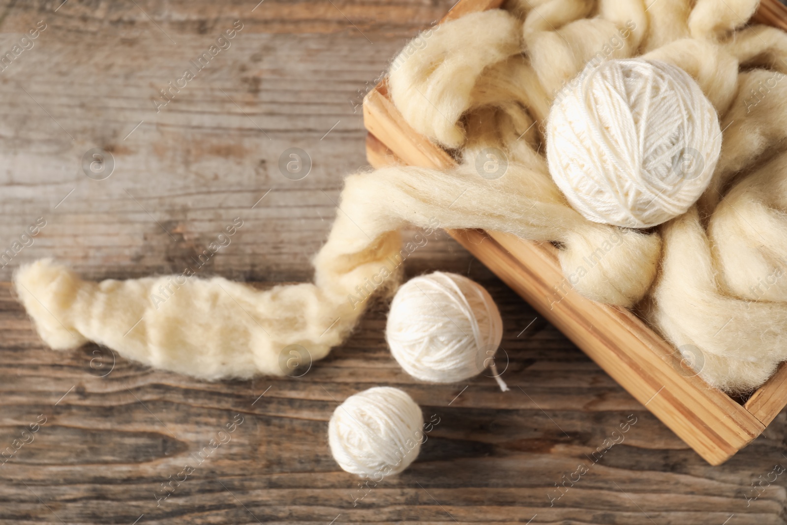 Felting wool and knitting yarn on wooden table, closeup Photo of Felting wool and knitting yarn on wooden table, closeup