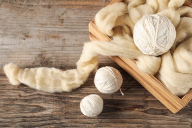 Photo of Felting wool and knitting yarn on wooden table, closeup