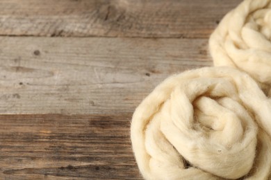 Photo of Felting wool on wooden background, closeup. Space for text
