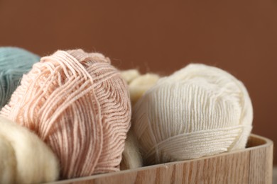 Photo of Felting wool and knitting yarn on brown background, closeup