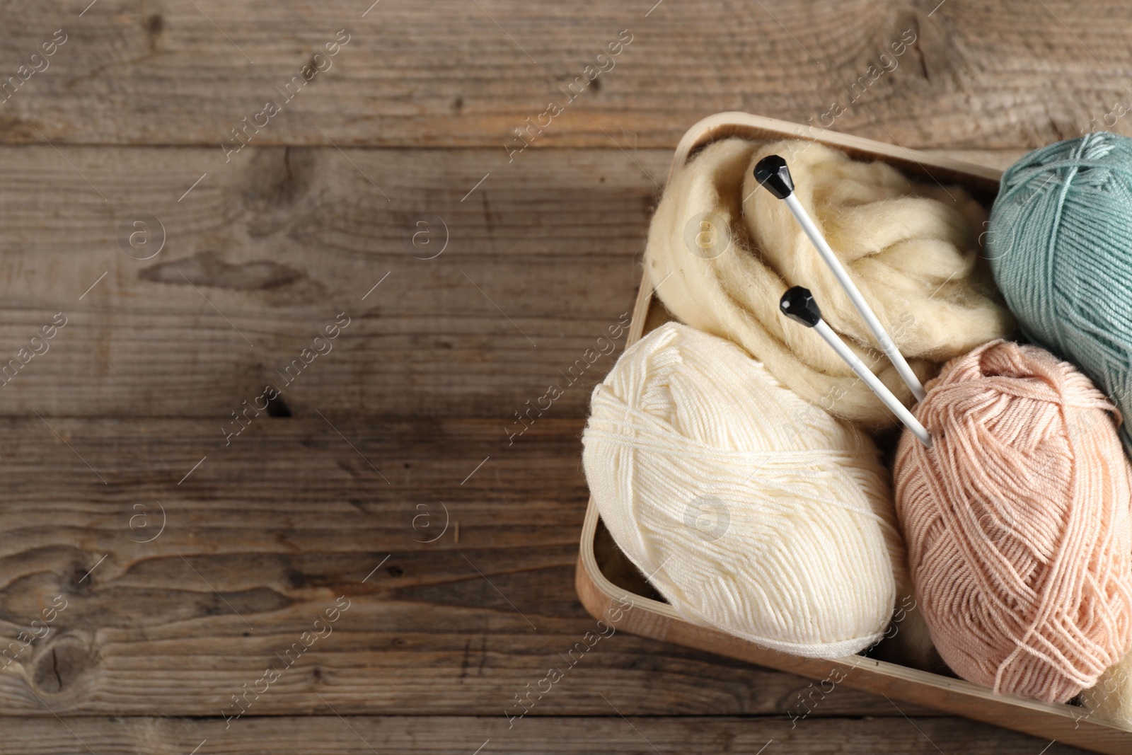 Felting wool and knitting yarn with needles on wooden table, top view. Space for text Photo of Felting wool and knitting yarn with needles on wooden table, top view. Space for text