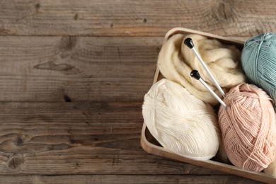 Photo of Felting wool and knitting yarn with needles on wooden table, top view. Space for text