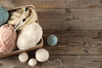 Photo of Felting wool and knitting yarn with needles on wooden table, top view. Space for text
