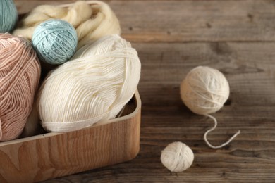 Photo of Felting wool and knitting yarn on wooden table, closeup