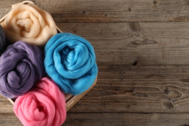 Photo of Colorful felting wool on wooden background, top view. Space for text