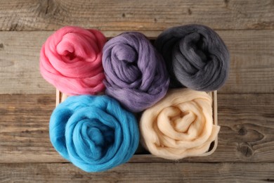 Photo of Colorful felting wool on wooden background, top view