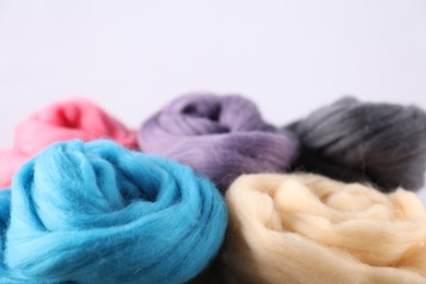 Photo of Colorful felting wool on light background, closeup