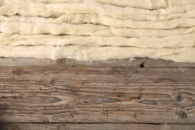 Photo of Felting wool on wooden background, top view. Space for text