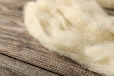 Photo of Natural felting wool on wooden background, closeup