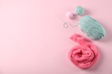 Photo of Felting wool and knitting yarn on pink background, flat lay. Space for text