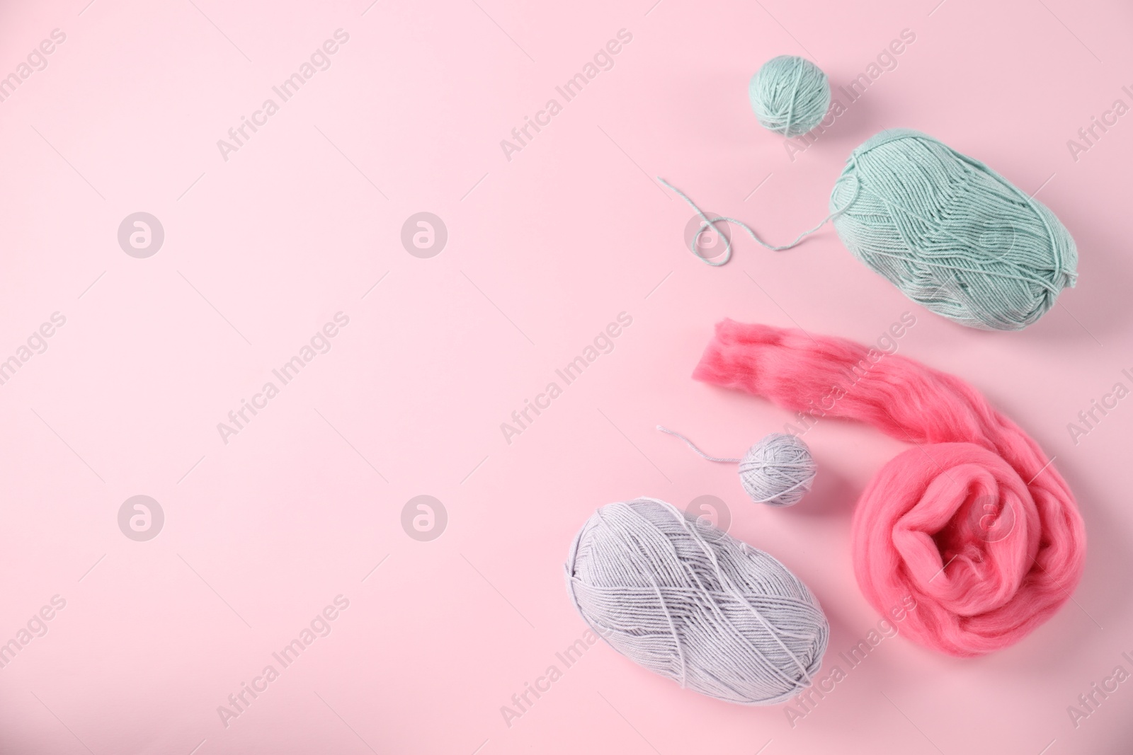 Felting wool and knitting yarn on pink background, flat lay. Space for text Photo of Felting wool and knitting yarn on pink background, flat lay. Space for text