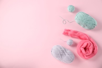 Photo of Felting wool and knitting yarn on pink background, flat lay. Space for text
