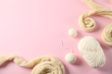 Photo of Felting wool and knitting yarn on pink background, flat lay. Space for text