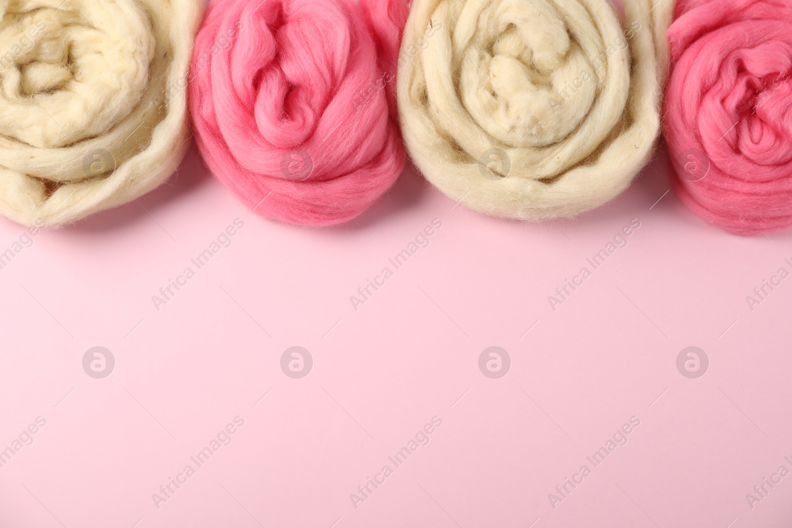 Colorful felting wool on pink background, flat lay. Space for text Photo of Colorful felting wool on pink background, flat lay. Space for text