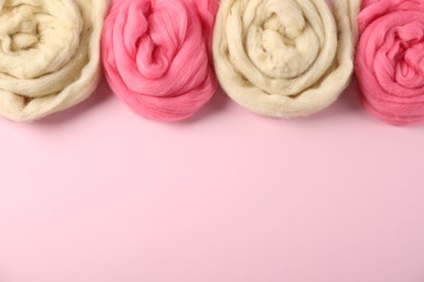 Photo of Colorful felting wool on pink background, flat lay. Space for text