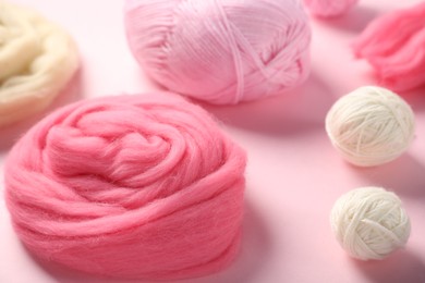 Photo of Felting wool and knitting yarn on pink background, closeup