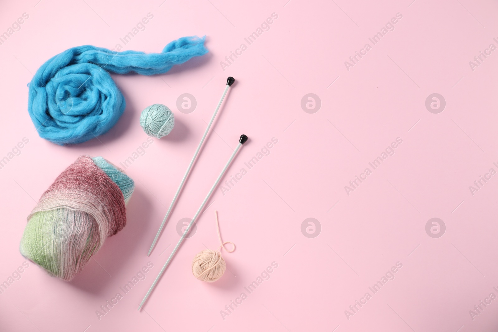 Felting wool and knitting yarn with needles on pink background, flat lay. Space for text Photo of Felting wool and knitting yarn with needles on pink background, flat lay. Space for text