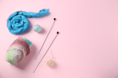 Photo of Felting wool and knitting yarn with needles on pink background, flat lay. Space for text