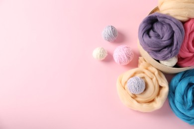 Photo of Felting wool and knitting yarn on pink background, flat lay. Space for text