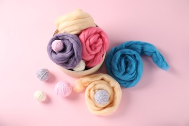 Photo of Felting wool and knitting yarn on pink background, flat lay