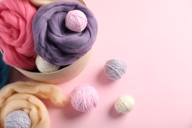 Photo of Felting wool and knitting yarn on pink background, above view. Space for text