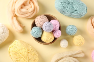 Photo of Felting wool and knitting yarn on beige background, flat lay