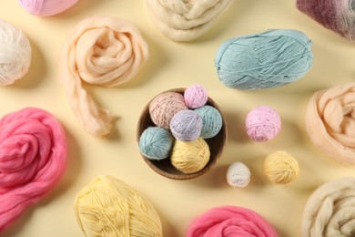 Photo of Felting wool and knitting yarn on beige background, flat lay