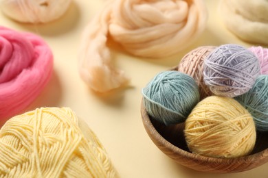 Photo of Felting wool and knitting yarn on beige background, closeup
