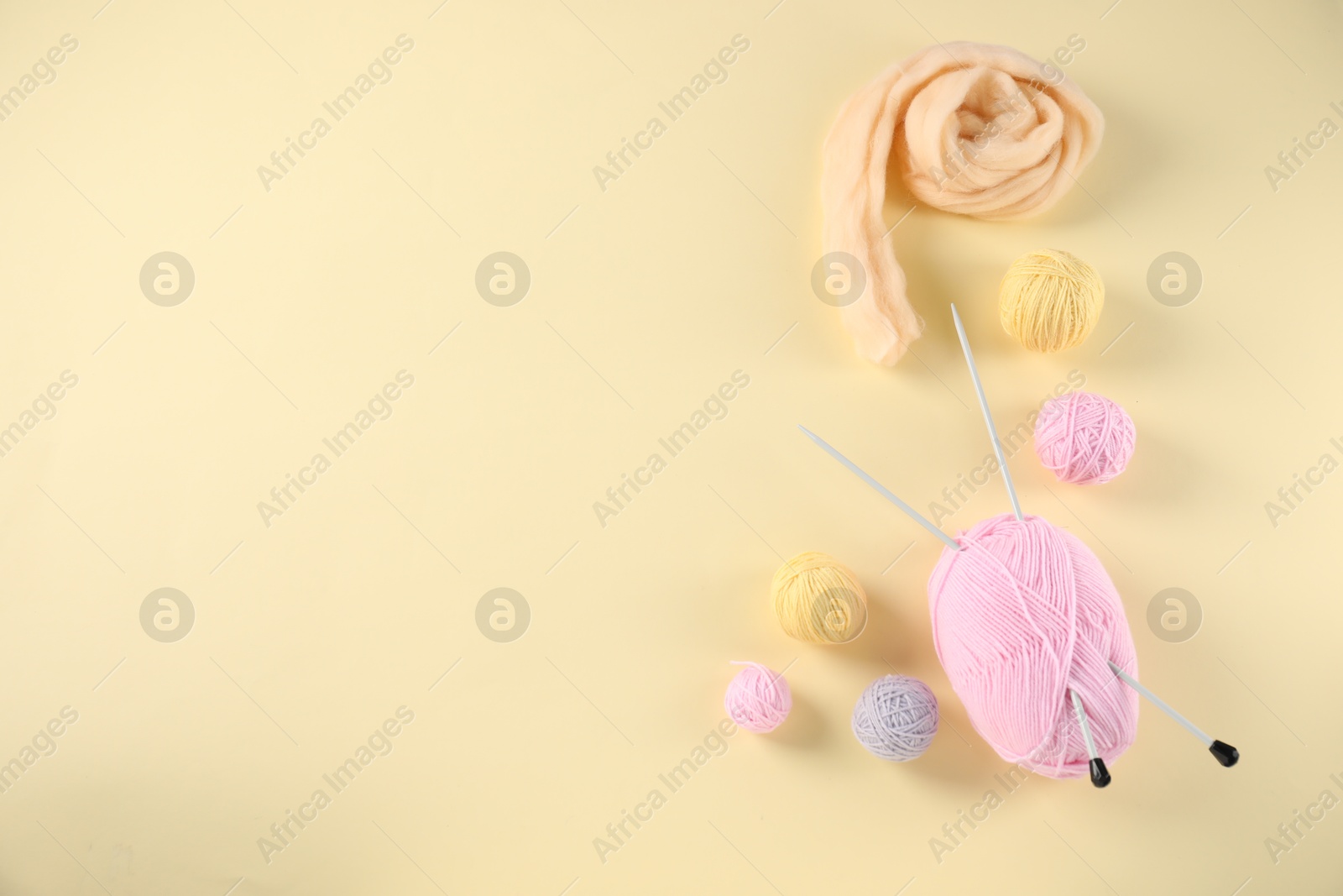 Felting wool and knitting yarn with needles on beige background, flat lay. Space for text Photo of Felting wool and knitting yarn with needles on beige background, flat lay. Space for text