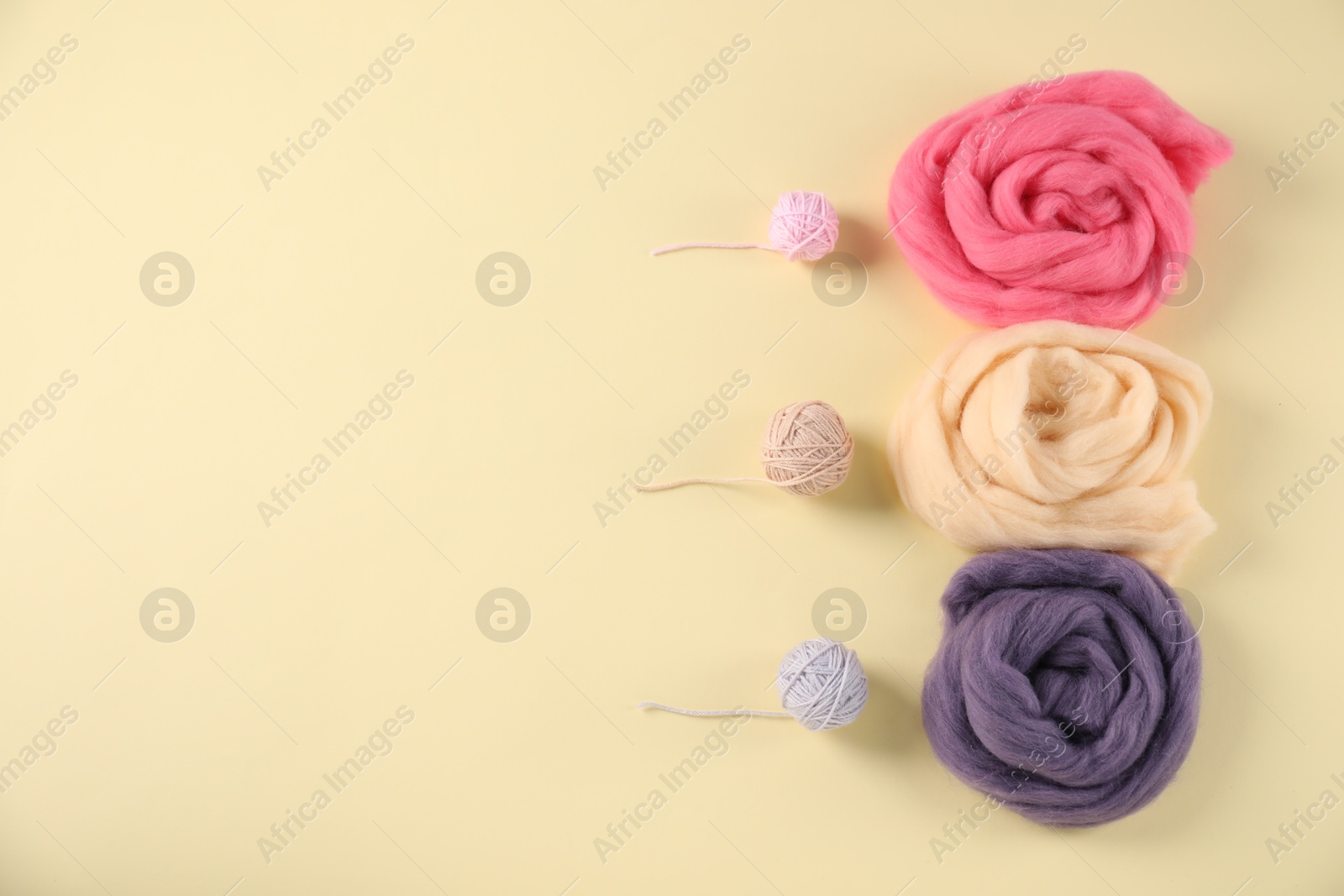 Felting wool and knitting yarn on beige background, flat lay. Space for text Photo of Felting wool and knitting yarn on beige background, flat lay. Space for text
