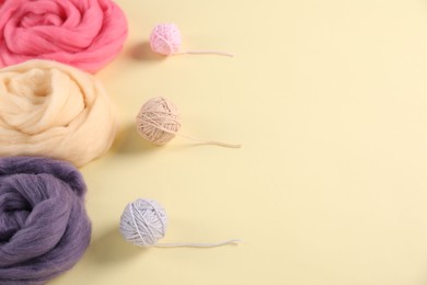 Photo of Felting wool and knitting yarn on beige background, closeup. Space for text