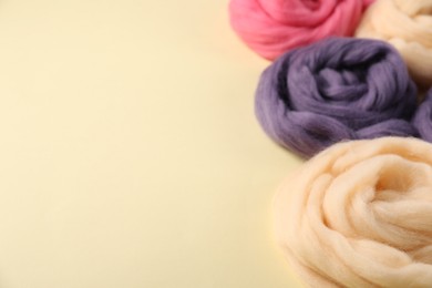 Photo of Colorful felting wool on beige background, closeup. Space for text